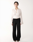 Person wearing a white blouse and black pants on a white background
