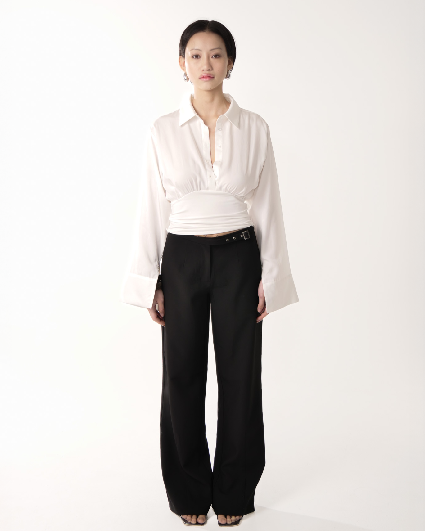 Person wearing a white blouse and black pants on a white background